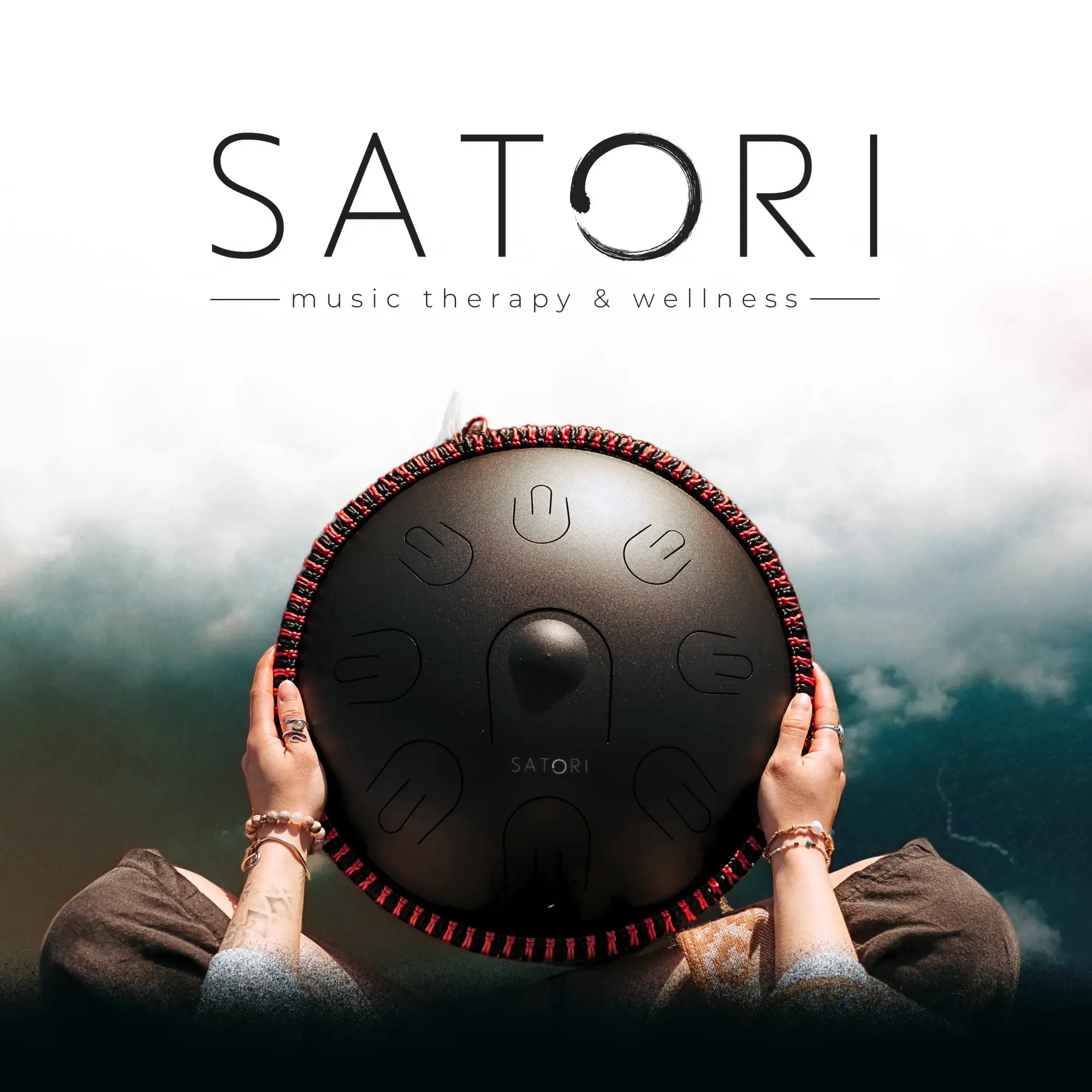 Black satori handpan with red braided edge and engraved tuning marks.