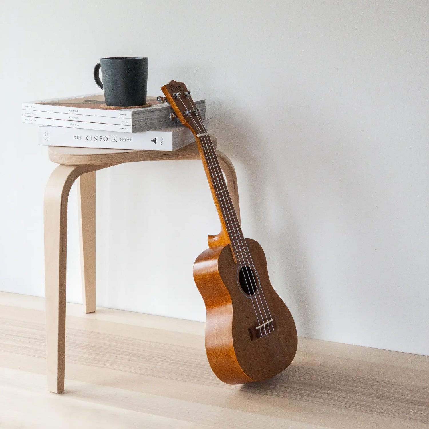 A polished wooden ukulele with a warm amber finish and natural wood grain, featuring a dark soundhole and silver-colored tuning pegs.