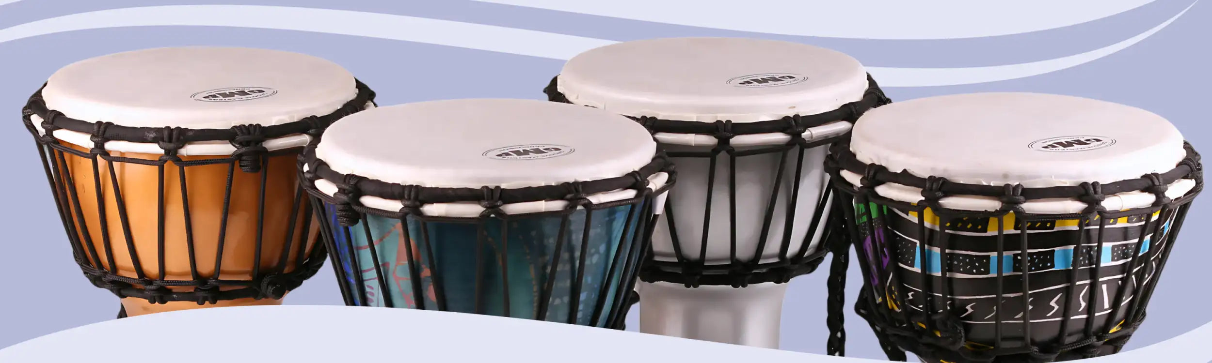 Set of four colorful djembe drums with white heads and black woven frames.