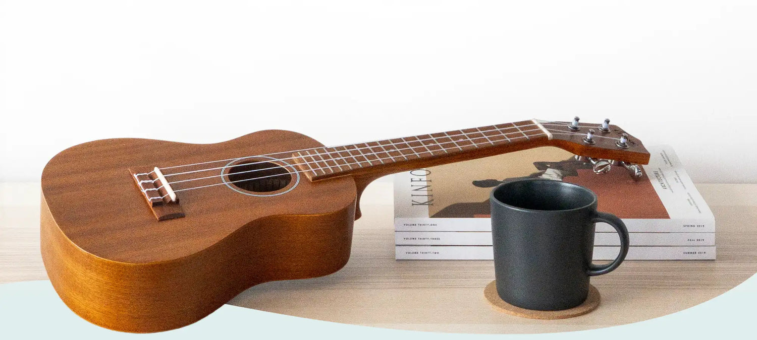 A warm-toned wooden ukulele with a glossy finish and natural wood grain, featuring a dark brown fretboard and silver tuning pegs.